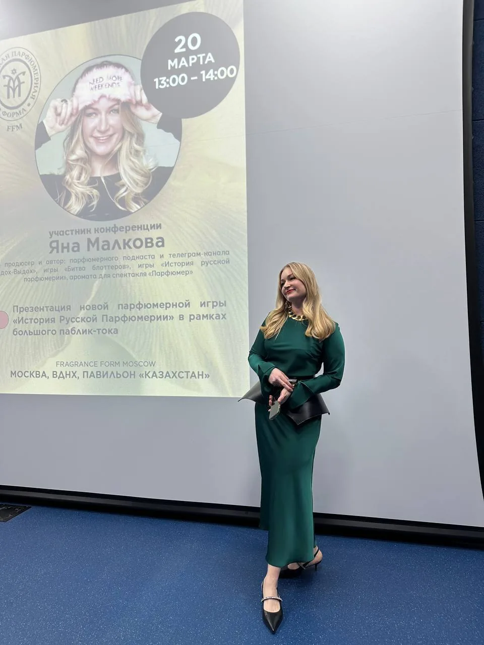 Яна Малкова выступает перед экраном с анонсом встречи